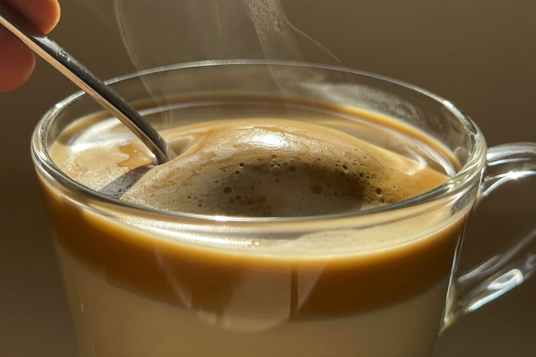 Cuchara revolviendo el café en una taza de vidrio