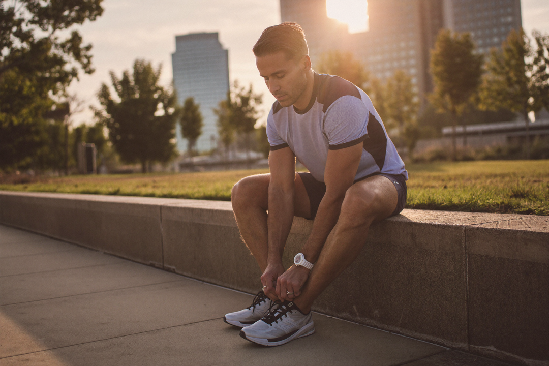 Hombre activo amarrando sus zapatos deportivos al amanecer